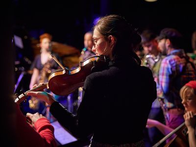 Photo taken of the back of a student tuning a violin